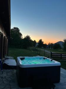 a hot tub in a yard with a sunset in the background at Plitvički San in Korenica