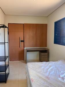 a bedroom with a bed and a wooden door at Suíte aconchegante no coração da Cidade in Sidrolândia +2 photos