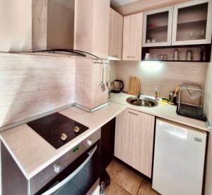 a small kitchen with a stove and a sink at Нашата къща in Sinemorets