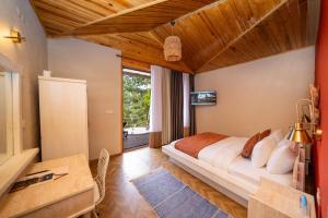 a bedroom with a bed and a desk and a window at Lov Faralya Adults Only in Faralya