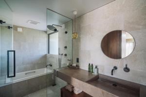 宮古島にあるvilla irifi 夕陽を望むヴィラの洗面台、浴槽、鏡のあるバスルーム