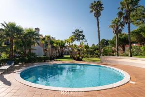 a swimming pool in a yard with palm trees at Casa da Isla - Praia del Rey Golf & Beach Resort in Amoreira