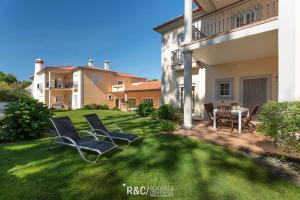 a lawn with chairs and a table in a yard at Casa da Isla - Praia del Rey Golf & Beach Resort in Amoreira