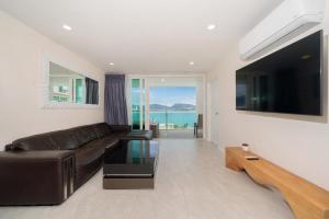 芭东海滩Private sea view apartment with jacuzzi at Baycliff的客厅配有真皮沙发和大电视