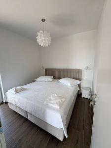 a white bedroom with a bed and a chandelier at Apartment Lana in Makarska