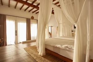una camera con letto a baldacchino bianco e tende di Lov Faralya Adults Only a Faralya