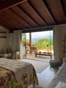 a bedroom with a bed and a large sliding glass door at Beautiful house overlooking the sea, swimming pool and Wi-Fi in Angra dos Reis