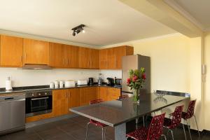 eine Küche mit Holzschränken und einem Tisch mit roten Stühlen in der Unterkunft Casa Pimenta in Fajã da Ovelha in Prazeres