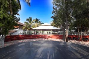 a large patio with an umbrella and trees and a building at Gubbi Goodu Green Resort in Bangalore