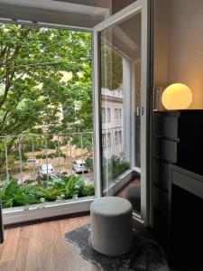 a living room with a large window and a stool at Central CityNest Studio No 8 in Wuppertal