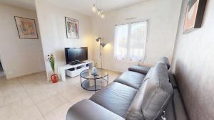 a living room with a blue couch and a television at Palm Cornue avec piscine privative in Saint-Gilles-Croix-de-Vie