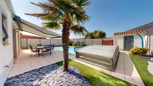 a backyard with a bed and a palm tree at Palm Cornue avec piscine privative in Saint-Gilles-Croix-de-Vie