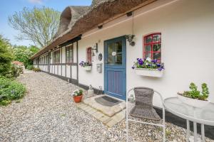 a white house with a blue door and a table at Naboløs Bed'n Kitchen - Nyborg in Bovense