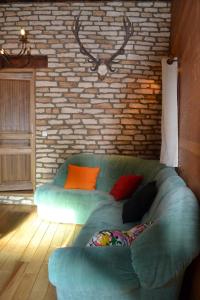 un sofá verde en una habitación con una pared de ladrillo en L'oustal Les Fayards, en Meyrueis