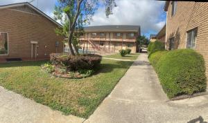 a sidewalk in front of a brick building with bushes at Hallmark Inn And Suites in Killeen
