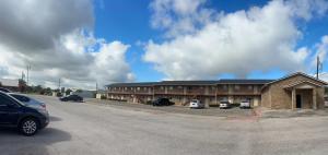 a large building with cars parked in a parking lot at Hallmark Inn And Suites in Killeen