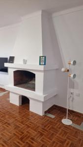 ein weißer Kamin in einem Wohnzimmer mit Holzböden in der Unterkunft Ericeira Breeze Villa in Ericeira