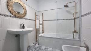 ein Badezimmer mit Waschbecken, Badewanne und Spiegel in der Unterkunft Ericeira Breeze Villa in Ericeira + 32 Fotos