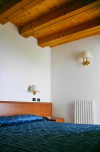 a bedroom with a blue bed and wooden ceilings at Hotel Al Poggio in Sestola