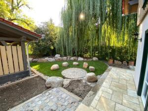 a garden with a weeping willow tree and a patio at Landhaus-Gutshaus in Ilsenburg