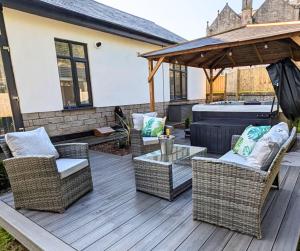 a patio with wicker chairs and a table and a hot tub at Eden Grove 2 Bed Holiday Retreat With Hot Tub in Kirkby Thore