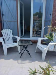 a porch with two white chairs and a table at Petit Lézard in Draguignan +1 photo