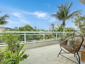 a balcony with a chair and palm trees at 200m do mar - AC - Piscina - Churrasqueira - 1 Suite in Guarujá
