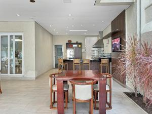 a kitchen and dining room with a wooden table and chairs at 200m do mar - AC - Piscina - Churrasqueira - 1 Suite in Guarujá