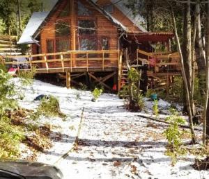 a log cabin in the woods with snow on the ground at Cabañas Alturas Doña Katalina in Chillán