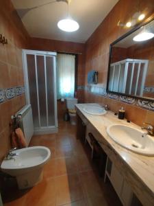 a bathroom with two sinks and a toilet and a mirror at Casa La Bolandrina Lago Barasona in La Puebla de Castro