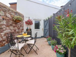 a patio with a table and chairs and plants at Lilly's Cottage in Dawlish