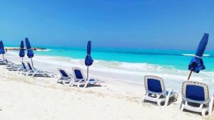 a group of chairs and umbrellas on a beach at شاليه بقرية اكوافيو in El Alamein