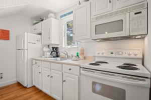 a white kitchen with a stove and a microwave at Private Deck Parking Walk to Town in Provincetown