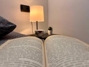 an open book on a table with a lamp and a cup at Appartamento al volt in Tenno