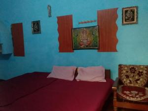 AyodhyaにあるL-99 Homestayのベッドと椅子があり、壁に絵が飾られている寝室