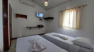 a room with two beds and a tv and a window at Pousada Casa de Jorge 2 in Lençóis