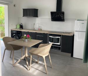 Una cocina con mesa y sillas y un refrigerador. en Villas Makandja - plage à 3 min à pied, piscines et jardins privés, en Sainte-Anne