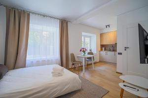 a bedroom with a bed and a table and a kitchen at Green Apartment with free parking in Kaunas
