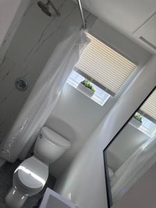 a white bathroom with a toilet and a window at Seabreeze Cottage in Lantana