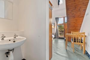a bathroom with a sink and a table with a chair at Errigal Hostel in Gweedore