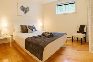 una camera da letto con un letto, una sedia e una finestra di Detente Nature bord de Lac #3 Spa Sauna & Foyer a Sainte Brigitte de Laval