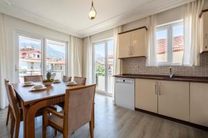 a kitchen with a table and chairs and a kitchen with windows at A spacious, comfortable and cozy apartment close to the center of Fethiye in Fethiye