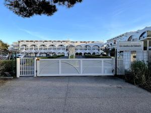un cancello bianco davanti a un edificio di Aux Jardins du Vidourle - 3 min à pied de la Plage, Parking, Clim & Wi-Fi a La Grande-Motte