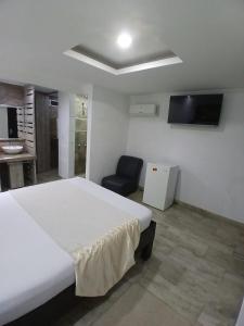 a bedroom with a large white bed and a chair at Hotel Plaza Norte Cali in Cali