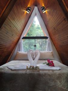 a bedroom with a bed with a love sign on it at Chalé romântico São Bento do Sapucaí - Jacuzzi - Chalé Gênova in São Bento do Sapucaí