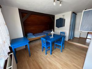 Una habitación con una mesa y sillas azules y una cama en Ubytovanie na súkromí, en Otilia