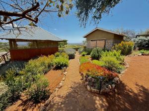a garden with flowers and a building in the background at 2 Authentic Mara Bush Cottages in Sekenani