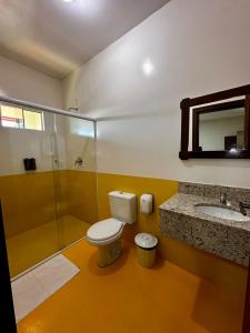 a bathroom with a toilet and a sink and a shower at Pousada Recanto das Cores in Penha