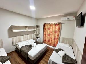 a hotel room with two beds and a television at Pousada Recanto das Cores in Penha
