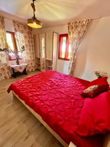 a bedroom with a large red bed with red sheets at Căsuța Dede in Buzau